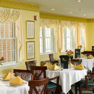 A cozy restaurant dining area with elegantly set tables and yellow decor.