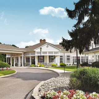 A picturesque residential building with a landscaped garden and circular driveway.