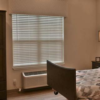 A cozy bedroom with a bed, window blinds, and wooden furniture.