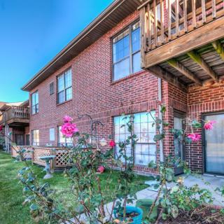 A red brick apartment complex with balconies and a blooming rose garden.