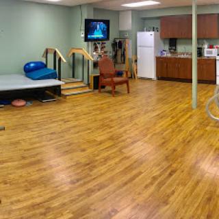 A spacious basement area featuring a kitchen, seating, and workout equipment.