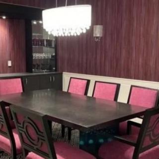 A modern dining room with a dark wooden table, upholstered chairs, and a stylish chandelier.