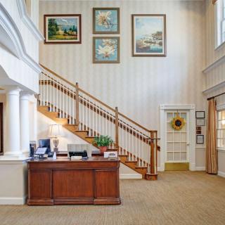 A welcoming lobby area featuring a wooden reception desk and an elegant staircase with framed artwork on the walls.