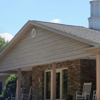 A house with a gable roof and a porch featuring rocking chairs.