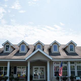 A classic suburban house with dormer windows and a porch, featuring an American flag.
