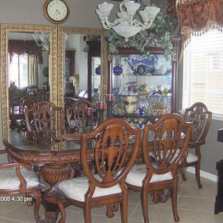 A classic dining room with ornate wooden furniture and a large mirror reflecting the space.