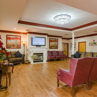 A cozy living room with comfortable seating and a fireplace under ambient lighting.
