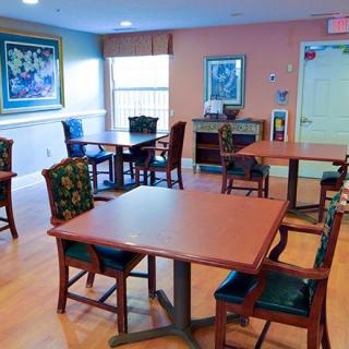 A cozy dining area with tables, chairs, and artwork on the walls.