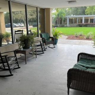 A cozy patio with rocking chairs and wicker furniture overlooking a lush garden.