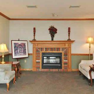 A cozy living room with a decorated fireplace, armchairs, and lamps.
