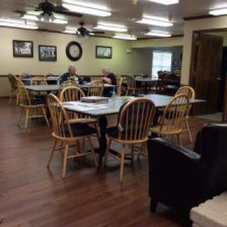 An empty dining area with wooden flooring and multiple tables and chairs.