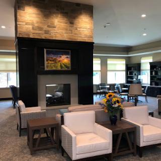 A stylish and modern lobby featuring a cozy seating area with white chairs, a stone fireplace, and vibrant floral arrangements.