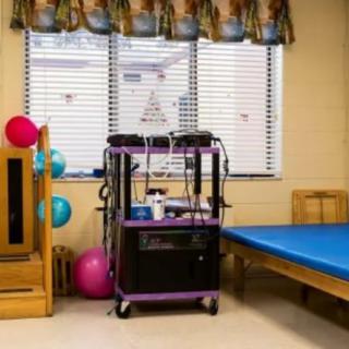 A therapy room equipped with exercise and rehabilitation tools, including a treatment bed and therapy balls.