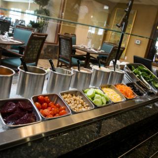A well-stocked salad bar at a restaurant with various fresh vegetables and toppings.
