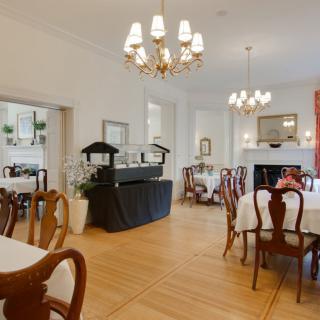 An elegant dining room with chandeliers, set tables, and wooden flooring.
