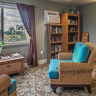 A cozy living room setup with a comfortable chair, bookshelves, and a window view.