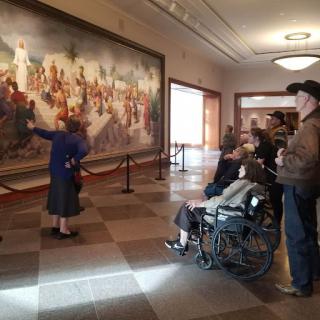 A guided tour at a museum, with visitors engaging with a large mural.