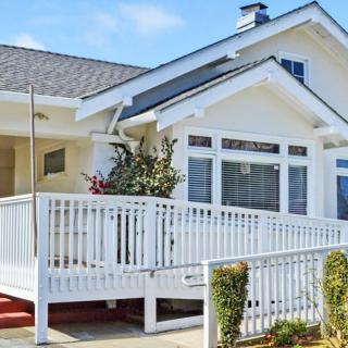 A charming white house with a front porch and accessibility ramp.