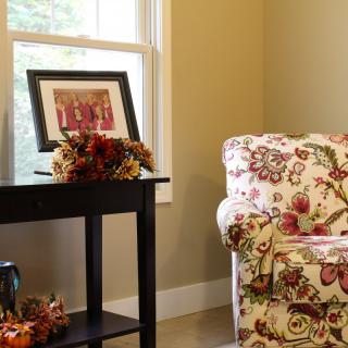 A cozy living room corner with a floral couch and autumn-themed decorations.