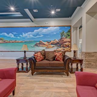 A cozy living room with elegant furniture and a large seascape painting on the wall.