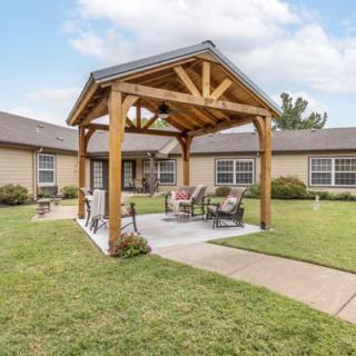 A cozy outdoor patio with a wooden pergola and seating area in a spacious yard.