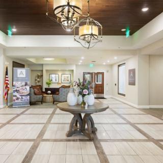 A spacious and elegantly decorated lobby with a central table and chandelier lighting.