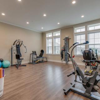 A well-lit home gym featuring various exercise equipment including treadmills and weights.