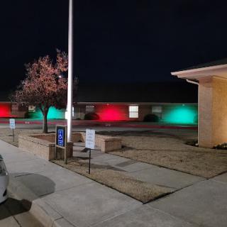 A view of a building illuminated with festive red and green lights at night.