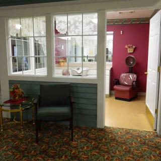 A cozy waiting area featuring a chair and an open doorway leading to another room.