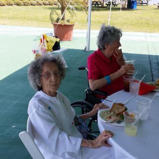 Elderly individuals enjoying a meal together outdoors.