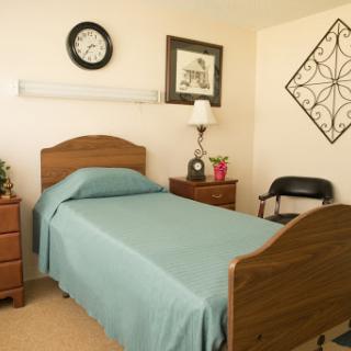 A cozy and well-arranged bedroom featuring a single bed with a blue cover, nightstands, and decorative elements.