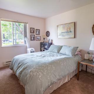 A cozy bedroom features a comfortable bed, artwork on the walls, and natural light streaming through the window.