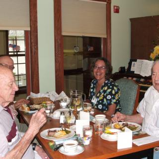 A group of seniors enjoying a meal together at a dining table.