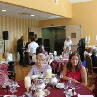 A group of people socializing at a decorated indoor event with dining tables.