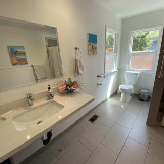 A modern bathroom with a large sink, mirror, and natural light from the window.