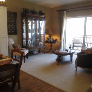 A cozy living room with a carpet, furniture, and large windows.