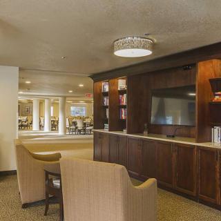 A cozy lounge area with comfortable seating, a TV, bookshelves, and warm ambient lighting.