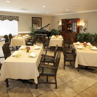 An elegantly decorated dining area with several tables and a piano in the corner.
