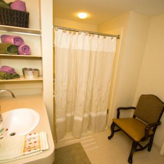 A cozy bathroom with a sink, shower curtain, and neatly organized shelves.