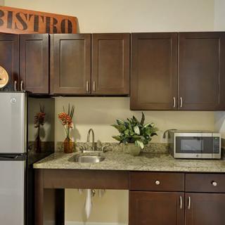 A modern kitchen with dark wood cabinets, a refrigerator, and a microwave on the countertop.