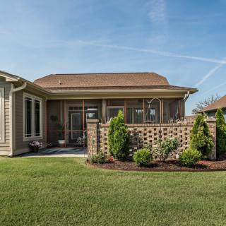A well-maintained backyard featuring a lush green lawn and a charming house with a small garden.