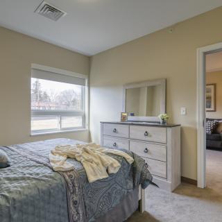 A cozy bedroom with a bed, dresser, and mirror.