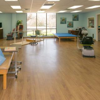 A spacious rehabilitation center with exercise equipment and therapy tables.