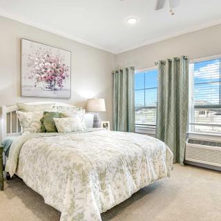 A cozy and well-lit bedroom with a large bed, soft bedding, and a nature painting above the headboard.