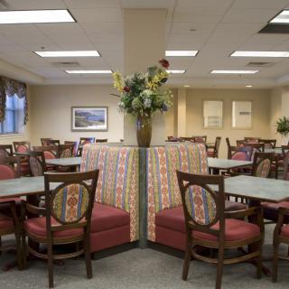 An empty dining area with well-arranged tables and chairs, featuring a central flower arrangement.