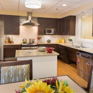 A modern kitchen with dark wood cabinets, stainless steel appliances, and a central island.