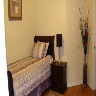 A cozy and minimalist bedroom with a single bed, nightstand, and decorative elements.