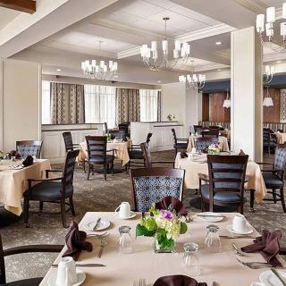 An elegant dining room with neatly arranged tables and chairs, adorned with chandeliers.