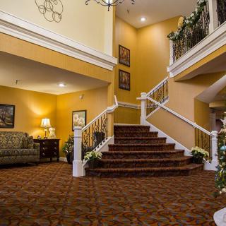 A warmly lit lobby with a staircase and elegant furnishings.