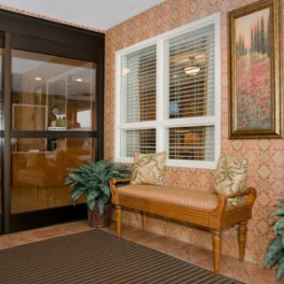 A cozy waiting area featuring a wooden bench, decorative plants, and artwork on the wall.